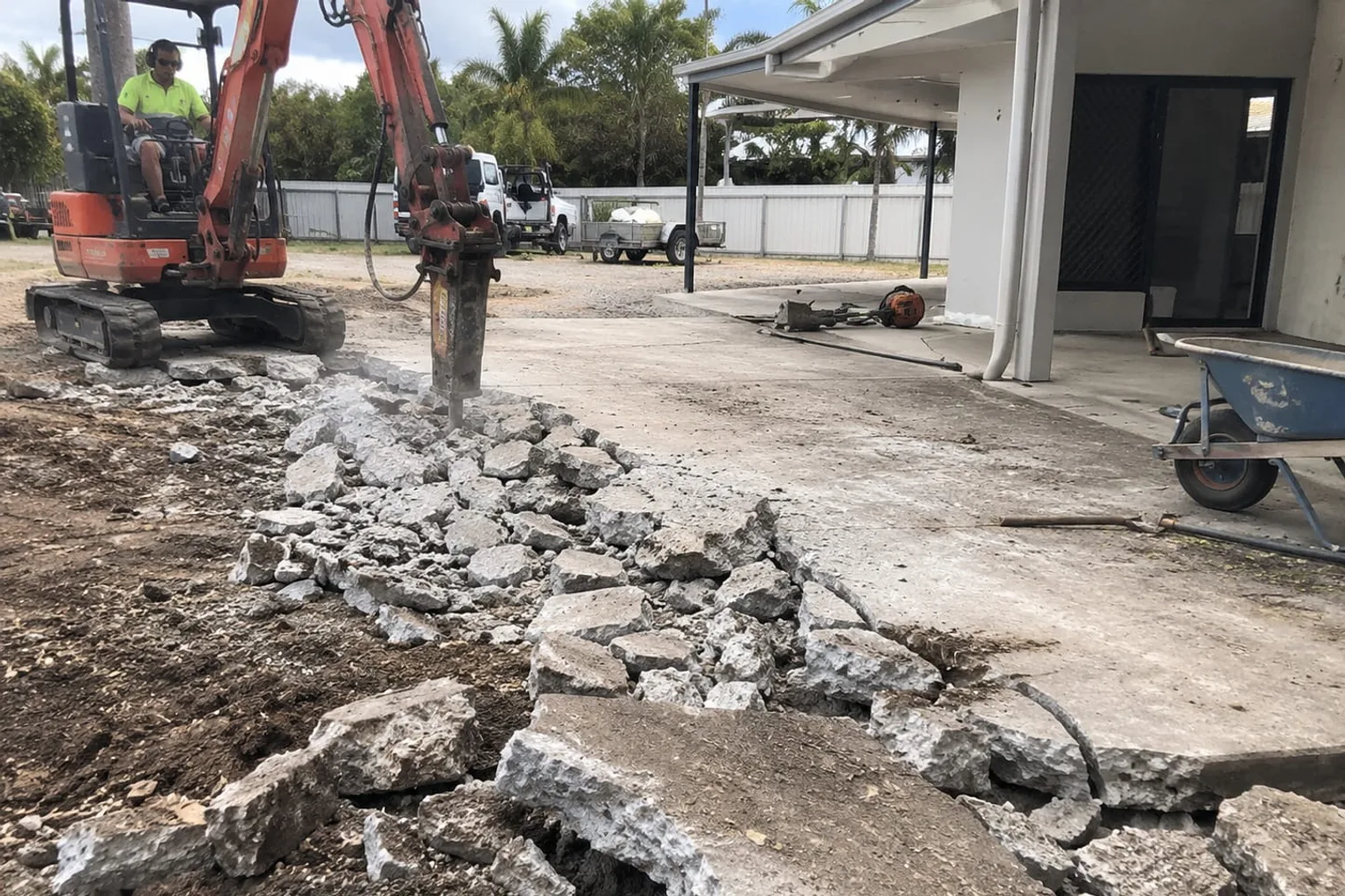 Excavator with a hydraulic breaker demolishing a concrete driveway at a Mackay property