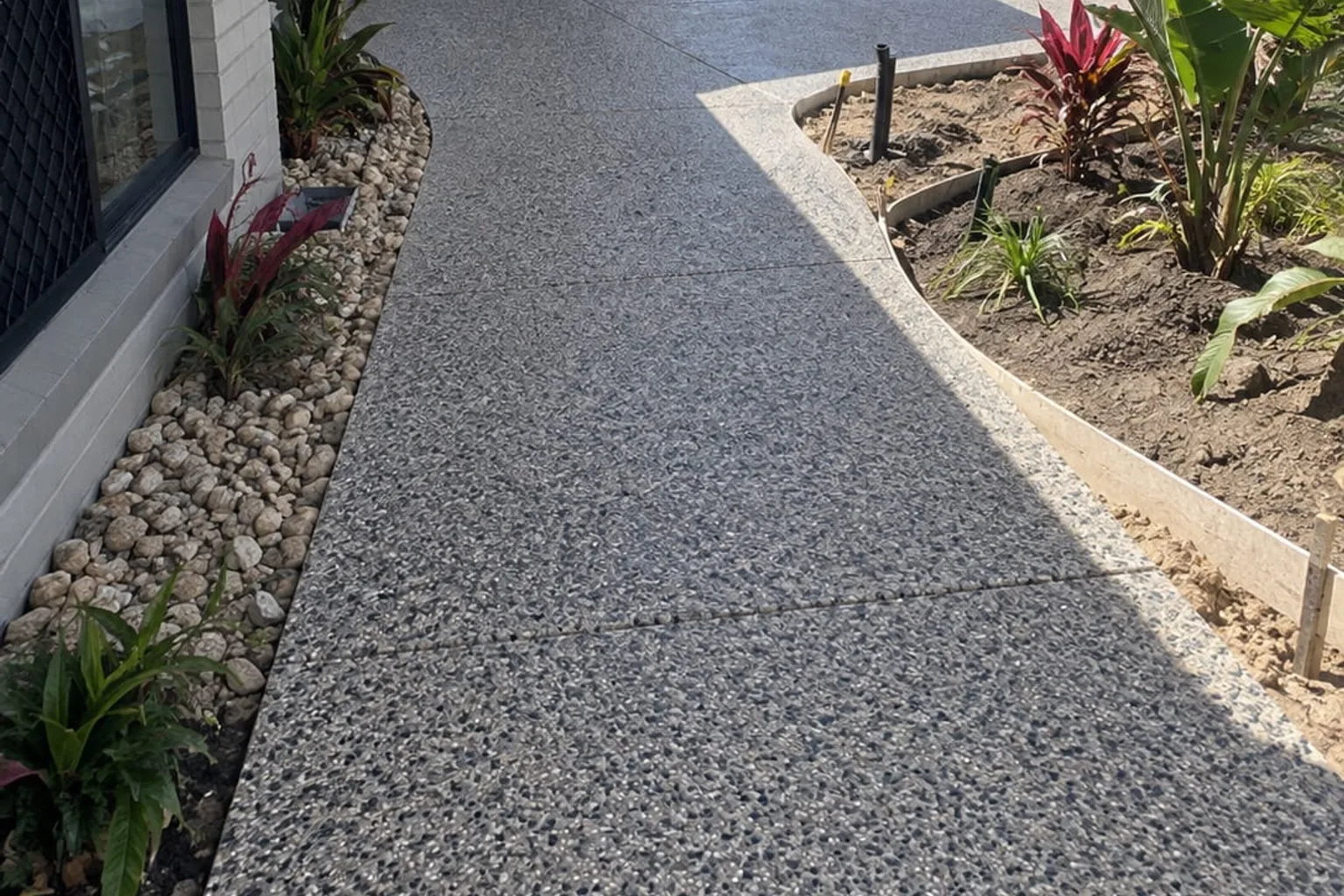Exposed aggregate concrete pathway running alongside a landscaped Mackay home