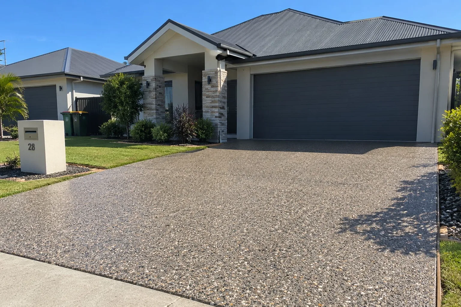 Wide exposed aggregate driveway running up to a double garage at a Mackay home