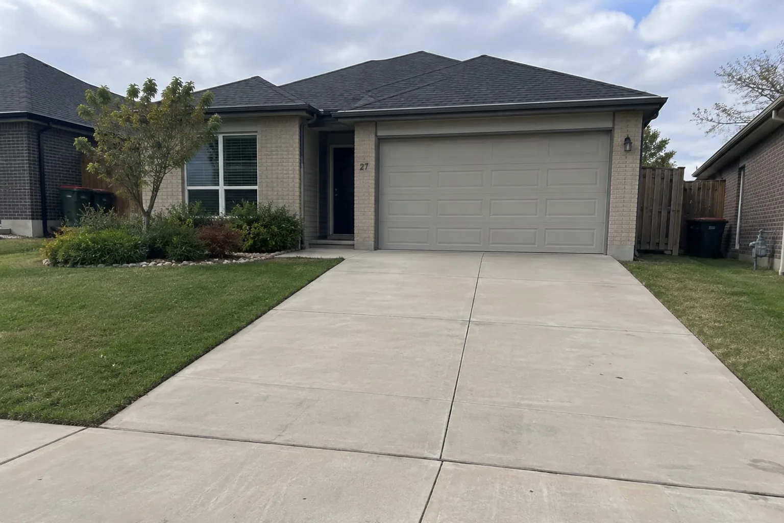 Plain grey concrete driveway running from the street to a double garage at a Mackay home