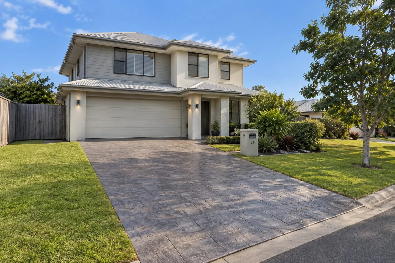 Stencilled concrete driveway with a brick-pattern finish leading to a double garage in Mackay